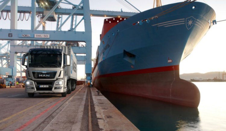 a large ship docked next to a MAN Diesel truck