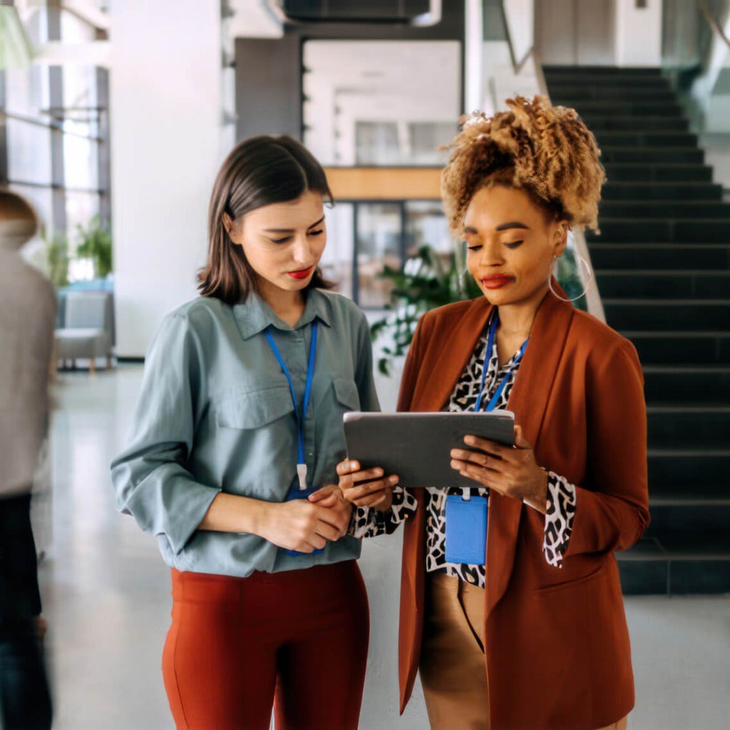 Two women having a discussion over a tablet device.