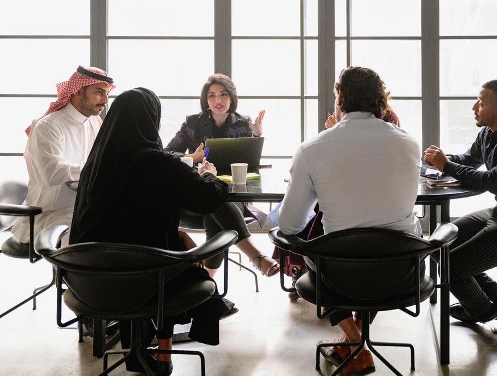 Co-workers sitting at a table having a meeting and discussing the digital future.